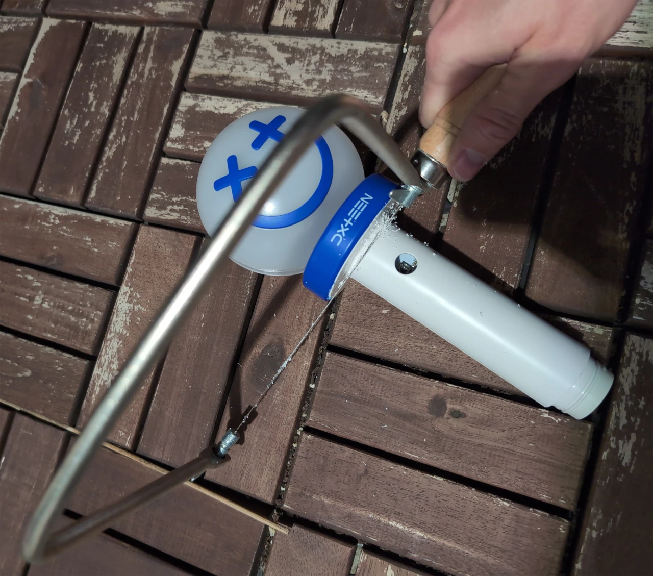 Using a hacksaw to cut through the plastic of the pen light